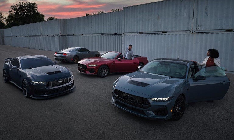 Four 2023 Ford Mustangs parked by shipping containers