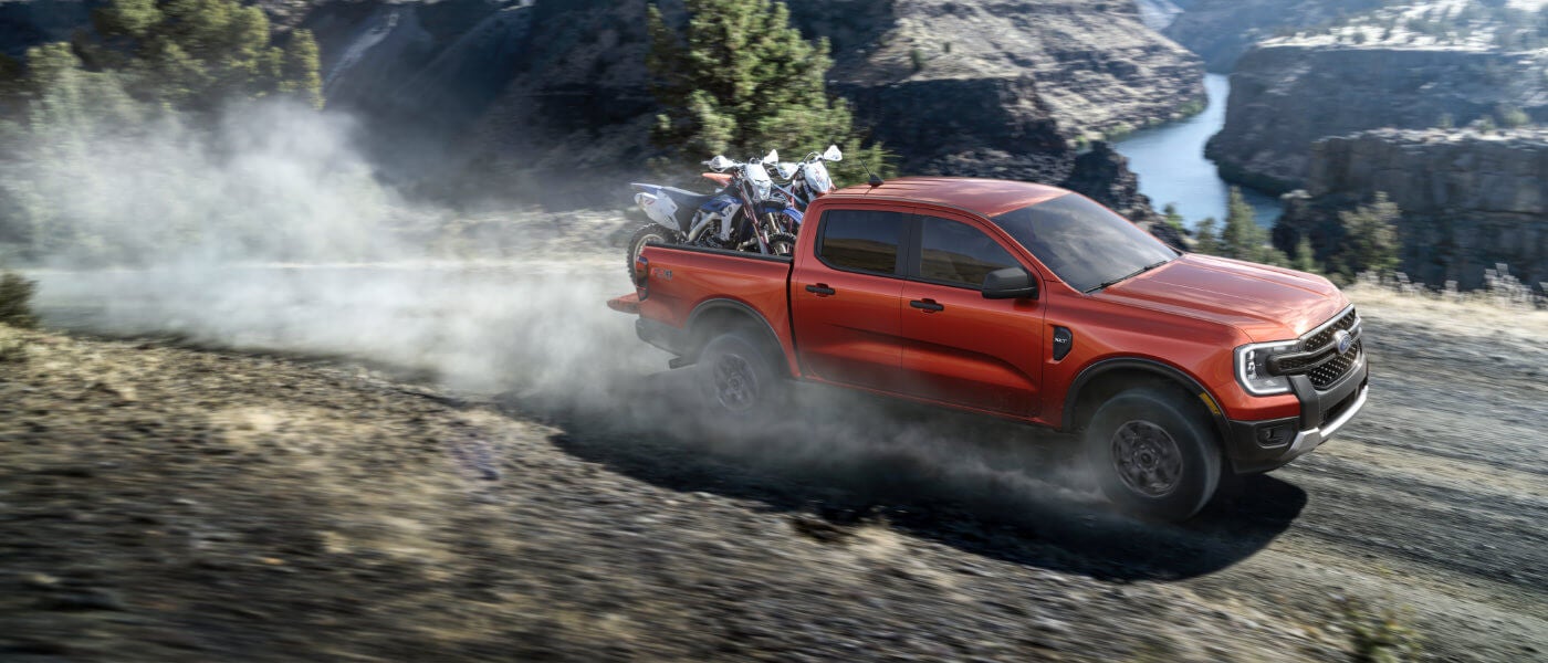 2026 Ford Ranger driving with bikes in bed on dusty trail